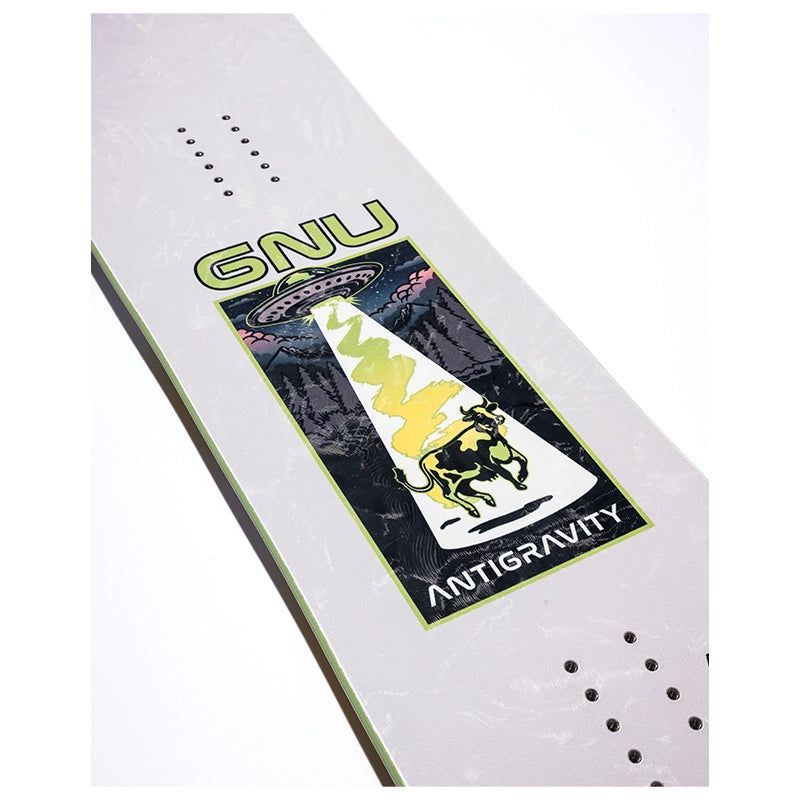 A close-up of a skateboard deck showing the underside, featuring a large graphic with the text 'GNU' and 'ANTIGRAVITY' around a UFO and bull illustration in green, yellow, black, and white on a light gray deck.