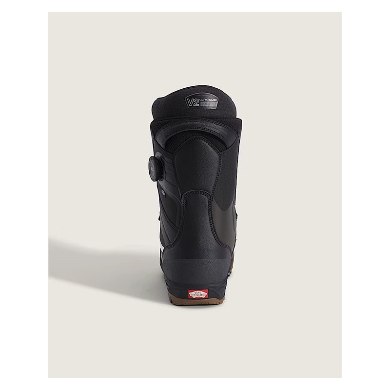 A single black Vans snowboard boot shown from the rear, featuring a dial closure and a small red Vans logo on the heel, set against a light beige background.
