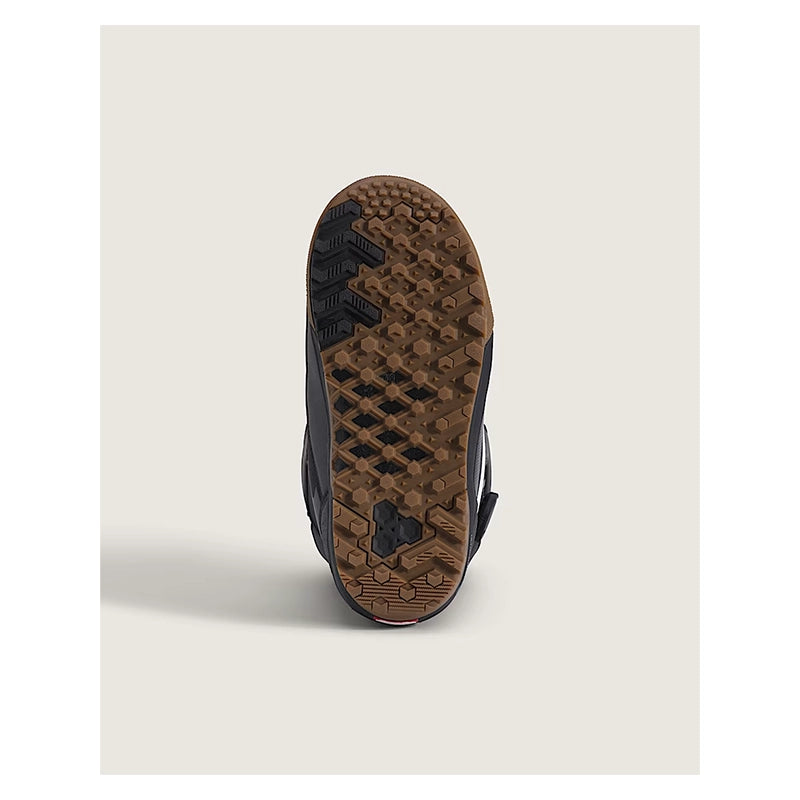 A close-up of the textured brown outsole of a black shoe, showing the tread pattern and a small black logo, set against a light beige background.