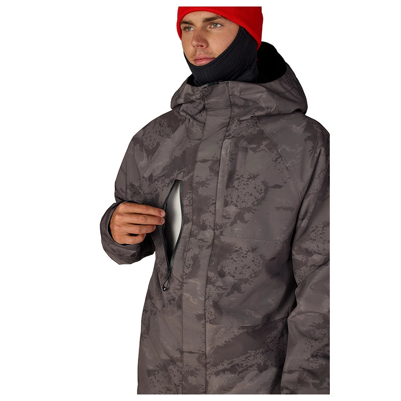 A man wearing a dark gray camouflage hooded jacket, a black neck gaiter, and a red beanie, shown against a plain white background.