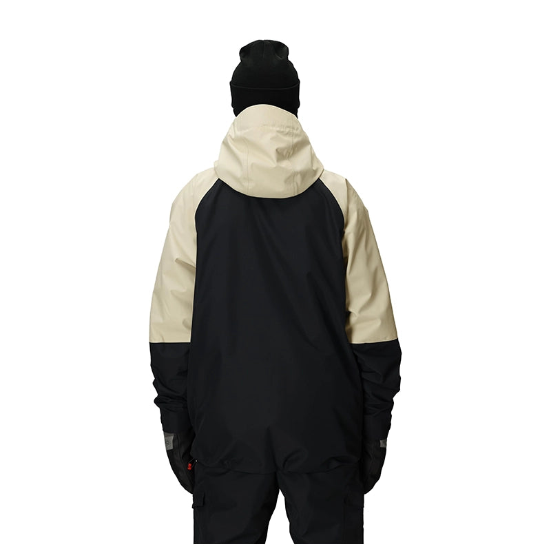 A person shown from the back wearing a color-blocked hooded jacket with a black body and sleeves, and a light beige upper back and hood, along with a black beanie against a plain white background.