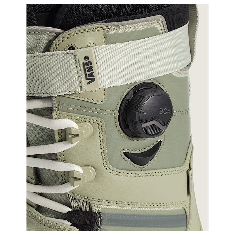 Close-up of a Vans snowboard boot in light sage green with white laces and a black BOA dial closure system.