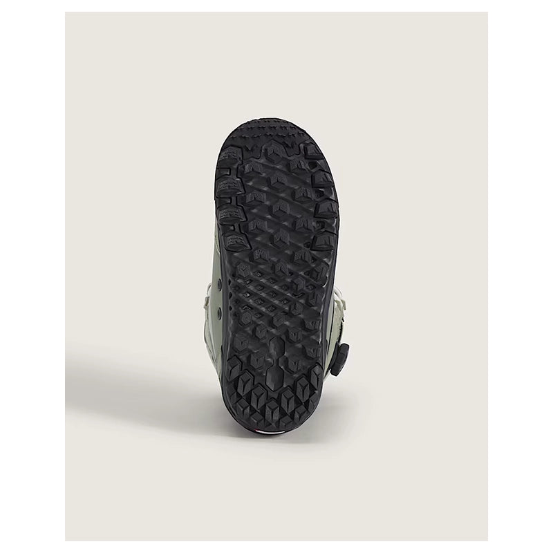 A close-up shot of the textured black rubber outsole of a shoe, showing its aggressive tread pattern, set against a solid light beige background.