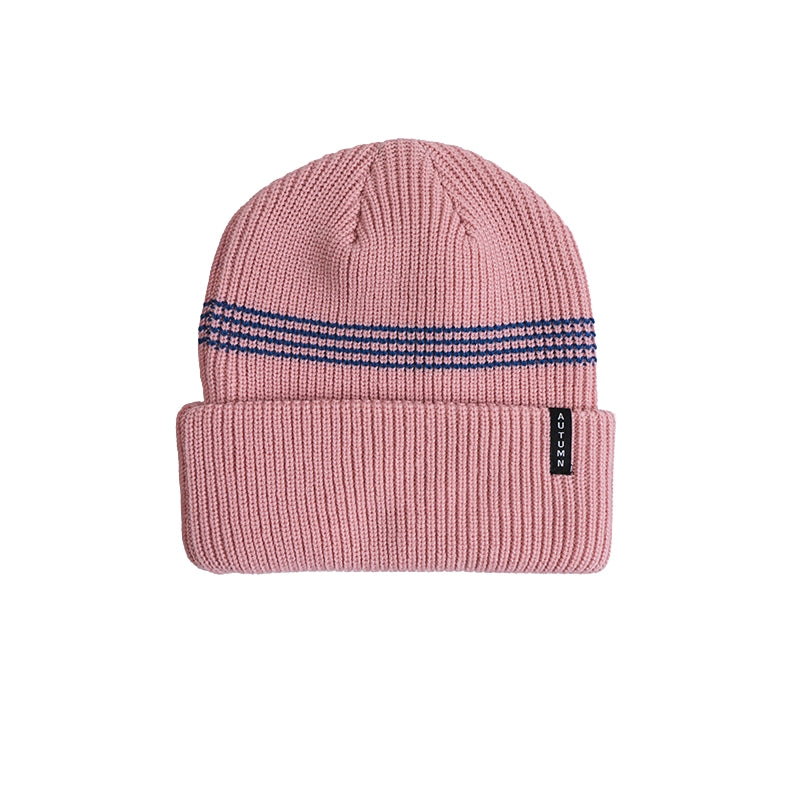A pink ribbed knit beanie hat with a folded cuff, featuring a navy blue and white patterned stripe across the top and a small black RECO brand tag on the cuff, shown against a plain white background.