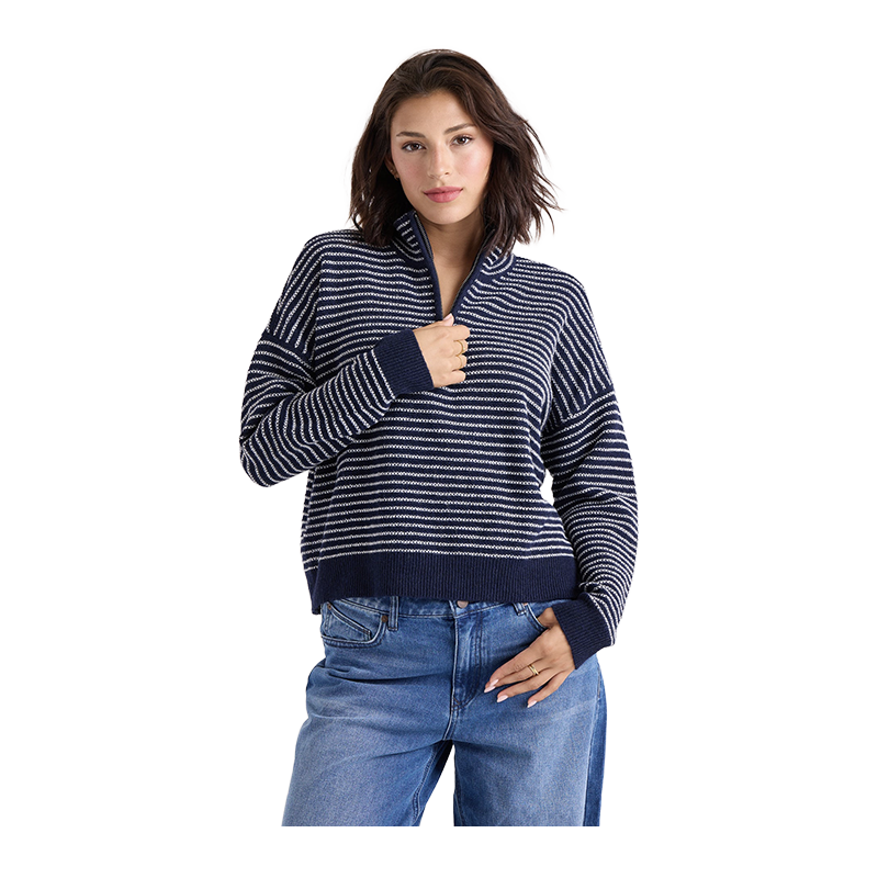 A woman modeling a navy blue and white striped quarter-zip knit sweater with a stand-up collar, paired with blue jeans, against a solid white background.