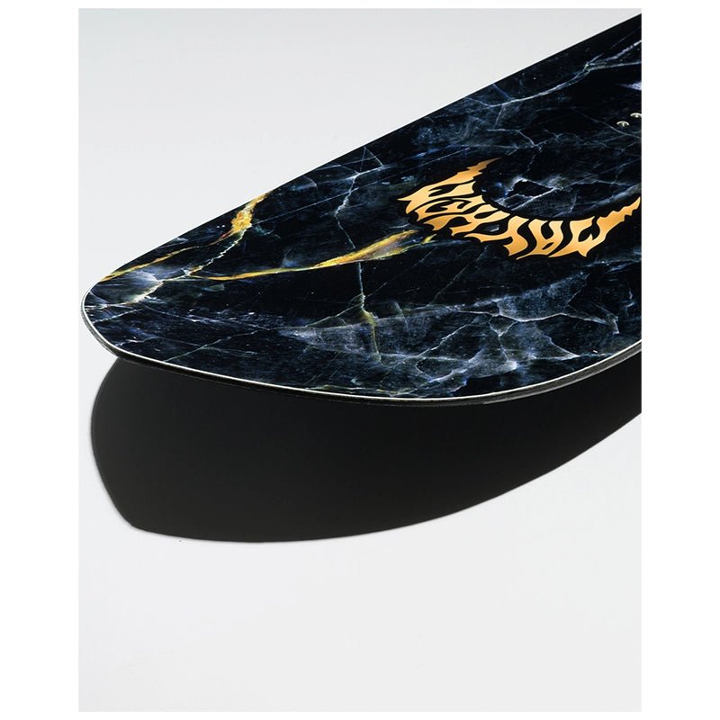 A close-up of a skateboard deck featuring a black and blue marble pattern with gold veins and a stylized gold logo, shown on a light gray background with a black shadow underneath.