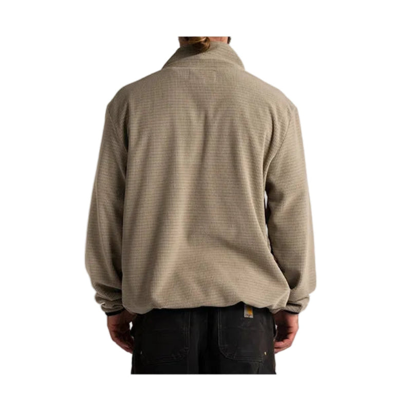 A person shown from the back wearing a light brown waffle-knit quarter-zip fleece pullover and dark pants, set against a plain light gray background.