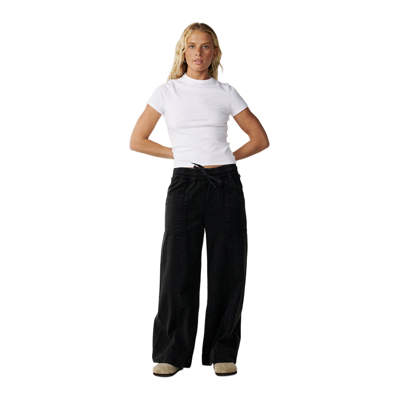 A woman modeling a white short-sleeve mock neck crop top and black wide-leg drawstring pants against a solid white background.
