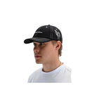 A man in a white t-shirt wearing a black baseball cap with white embroidery, shown in profile against a light gray background.
