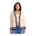 A woman modeling a cream cable-knit cardigan with navy blue trim and wooden buttons, paired with a matching cream crop top and blue jeans, against a solid white background.