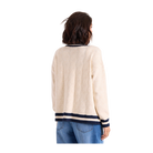A woman shown from the back wearing a cream-colored cable-knit sweater with navy and cream striped trim at the collar, cuffs, and hem, paired with blue jeans against a plain white background.
