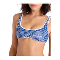 A woman wearing a blue and white paisley print bralette against a light beige background.