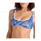 A woman wearing a blue and white paisley print bralette against a light beige background.