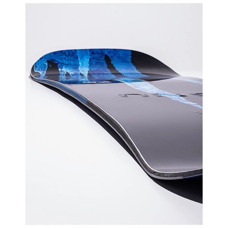 A close-up of a snowboard tail showing a dark gray base with a blue and black graphic pattern on the top sheet, photographed on a clean white background.