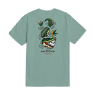 A sage green short-sleeve t-shirt shown from the back, featuring a graphic of a skull-headed alligator, green watermelons, and orange flowers with the text 'DARK SEAS' and 'MONTREAL' printed below.