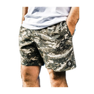 Person wearing camouflage shorts with a brand logo, standing outdoors.