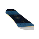 A snowboard shown from a high angle on a white background, featuring a dark navy blue base with a wood grain pattern in blue, yellow graphic details, and a white logo in the center.