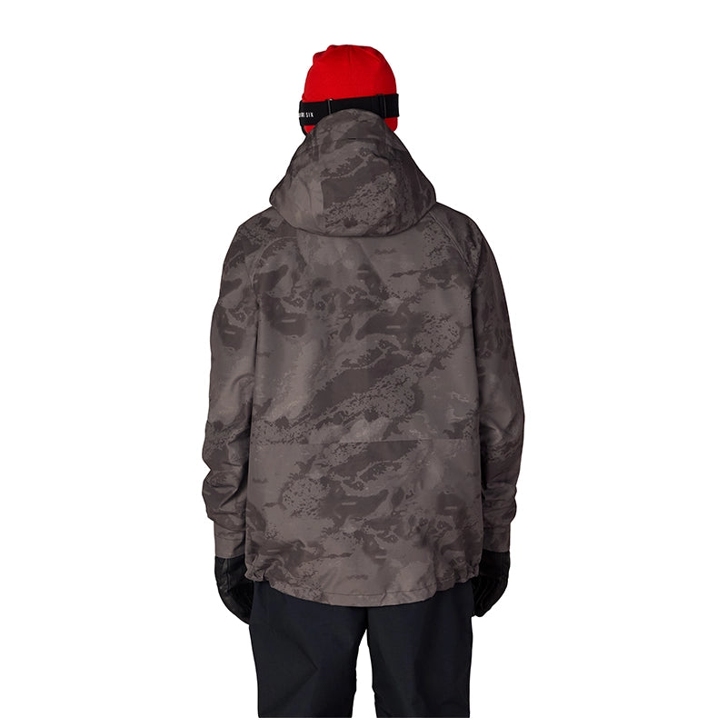 A person shown from the back wearing a dark gray and black camouflage hooded jacket, a bright red beanie, black gloves, and dark pants against a plain white background.