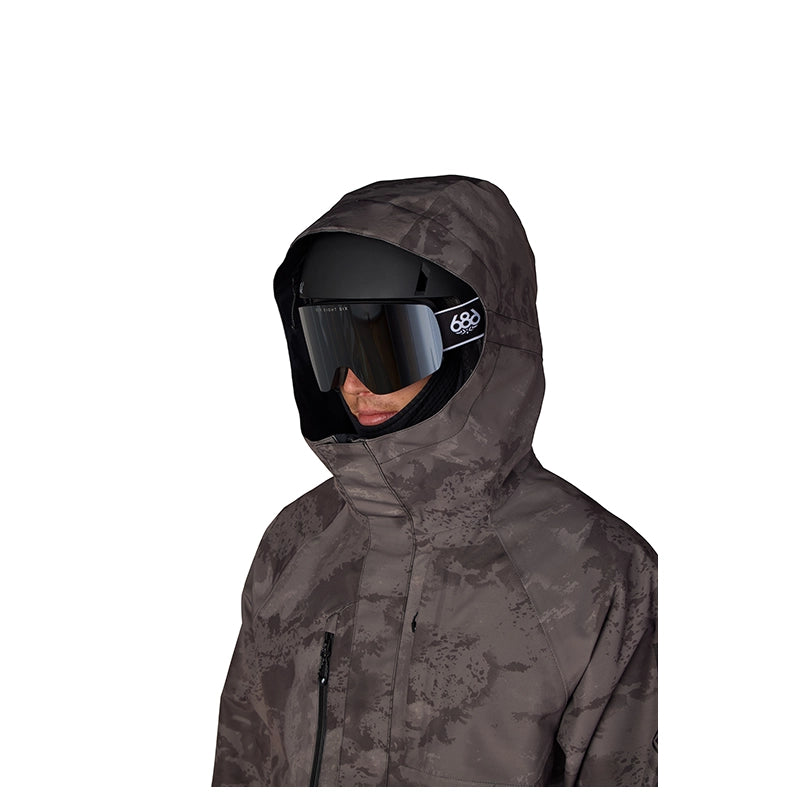 A person wearing a dark gray and black camouflage hooded ski jacket with black ski goggles, shown against a plain white background.