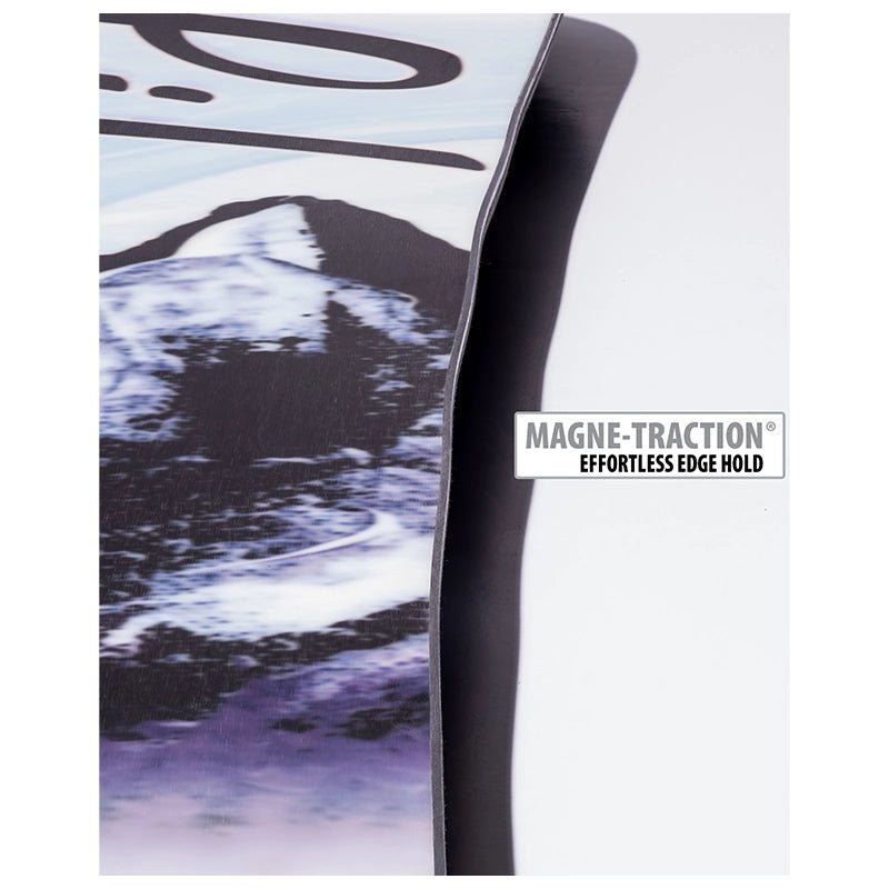 Close-up of a snowboard edge showing the black base, a printed mountain graphic in black, white, and purple, and a white label that reads MAGNE-TRACTION EFFORTLESS EDGE HOLD.