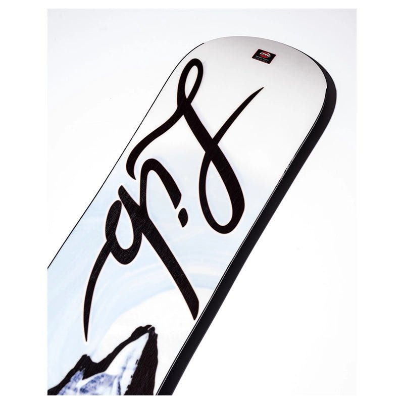 A close-up of a snowboard featuring a large black stylized logo on a white base with a light blue and black mountain graphic near the bottom.