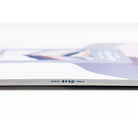 A close-up of a stack of white paper sheets with a thin gray edge and small printed text reading 'nitro drop 140 g'. The top sheet is blurred in the background, showing faint pastel artwork.