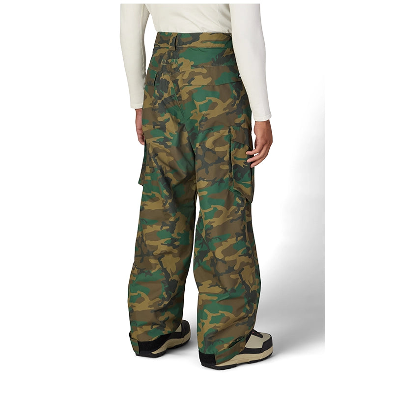 A person shown from the back wearing wide-leg camouflage cargo pants, a white long-sleeve top, and black-and-beige shoes against a light gray studio background.