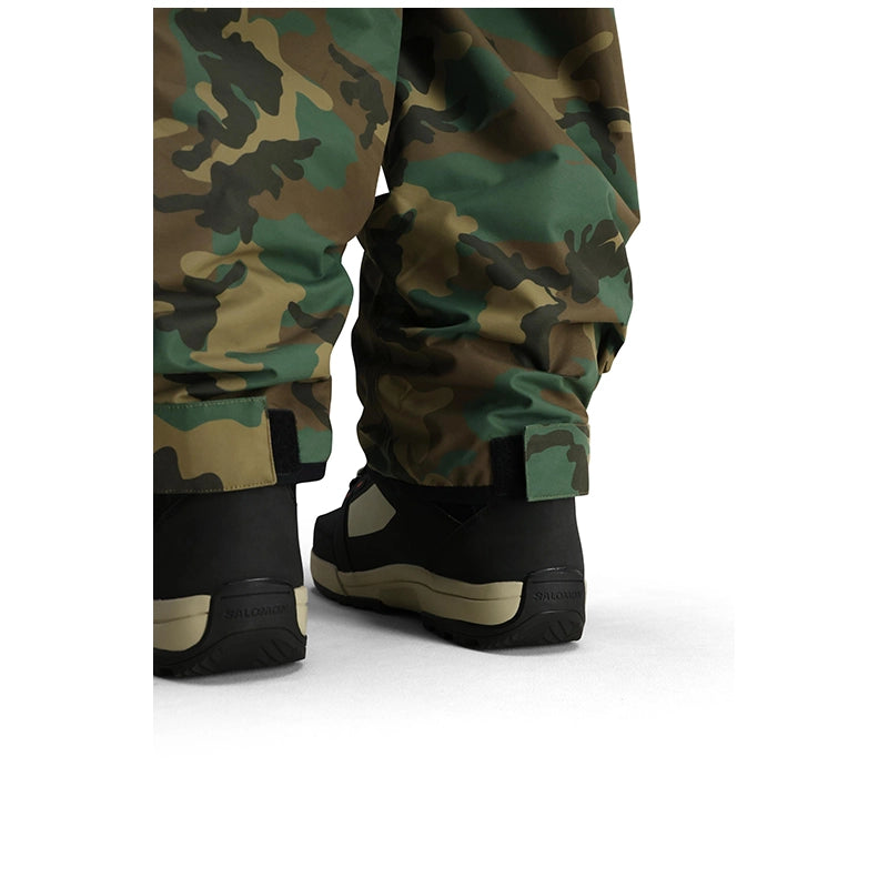 Close-up of camouflage snow pants with black and tan snowboard boots, shown from the back against a white background.