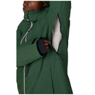 A close-up of a person wearing a dark green waterproof jacket, showing the high collar, a zippered pocket opening with a striped lining, and dark cuffs.
