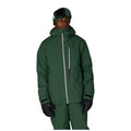 A man wearing a dark green ski jacket and matching ski pants, black gloves, and a black beanie with goggles, photographed against a solid white background.