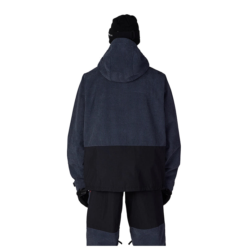 A person shown from the back wearing a dark hooded jacket with a dark ribbed upper section and black lower section, paired with dark pants and a black beanie, on a plain white background.