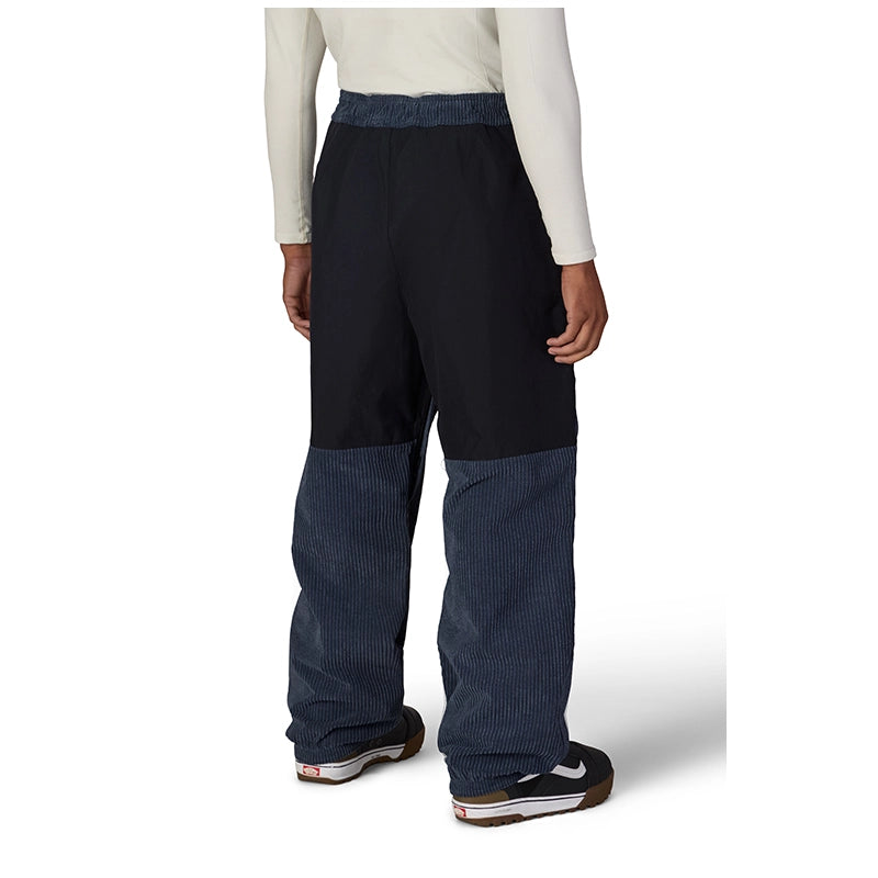 A person shown from the back wearing wide-leg pants with a solid black upper section and dark blue ribbed lower legs, paired with a cream long-sleeve top and black sneakers.