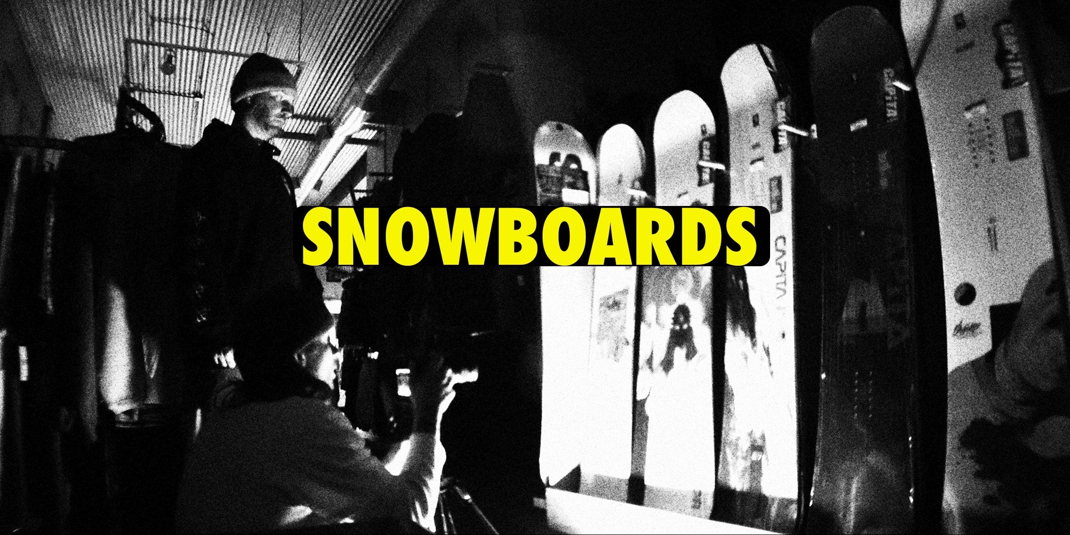 Black and white photo of people with snowboards, text 'SNOWBOARDS' in yellow.