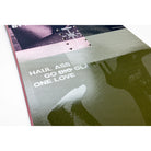 A close-up of a printed music cover or booklet page with the text 'HAUL ASS CO-DOG-CLAM ONE LOVE' over a striped gray-green background and a dark silhouette, photographed on a white surface.