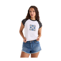 A woman modeling a white raglan t-shirt with dark gray sleeves and collar, featuring a blue graphic print on the chest, paired with denim shorts against a plain white background.