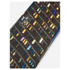 A close-up of a hair color swatch chart or display card showing multiple strands of hair in different shades, including dark brown, black, blonde, blue, purple, and green, with a visible 'RUDE KNIFE' label.