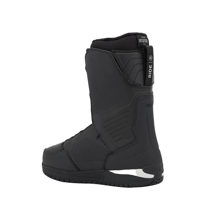 A black snowboard boot shown from the side against a light gray background. The boot features a padded collar, a heel strap with a white 'RIDE' logo, and a white accent near the sole.
