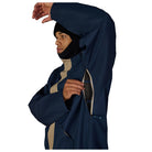 A man wearing a navy blue hooded jacket with a beige inner collar, shown from the side against a white background. He is pulling up the hood over his head and adjusting a zippered pocket on the sleeve.