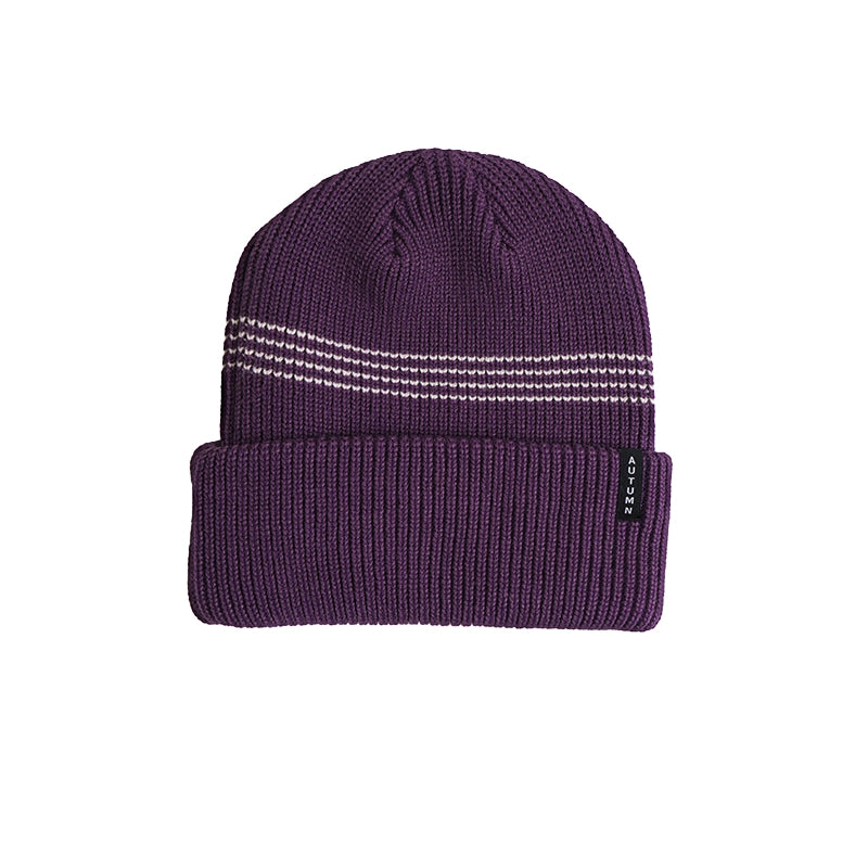 A dark purple ribbed knit beanie hat with three horizontal white stripe details on the crown and a small black brand tag on the folded cuff, shown against a plain white background.