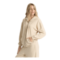 A woman modeling a matching beige zip-up hoodie and sweatpants set against a solid white background.