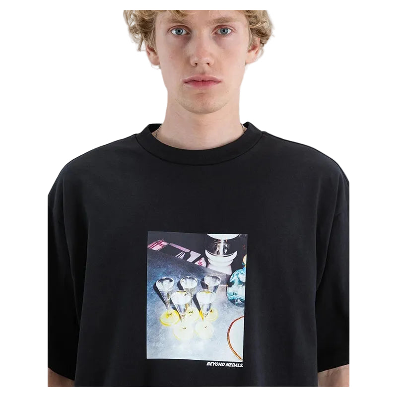 A model wearing a black oversized crewneck t-shirt with a square graphic print on the front depicting cocktail glasses and the text 'BEYOND MIDDLE'.