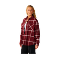 A woman modeling a burgundy red plaid flannel shirt with white stripes, worn open over a white undershirt and black pants, against a solid white background.