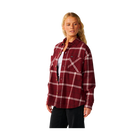 A woman modeling a burgundy red plaid flannel shirt with white stripes, worn open over a white undershirt and black pants, against a solid white background.