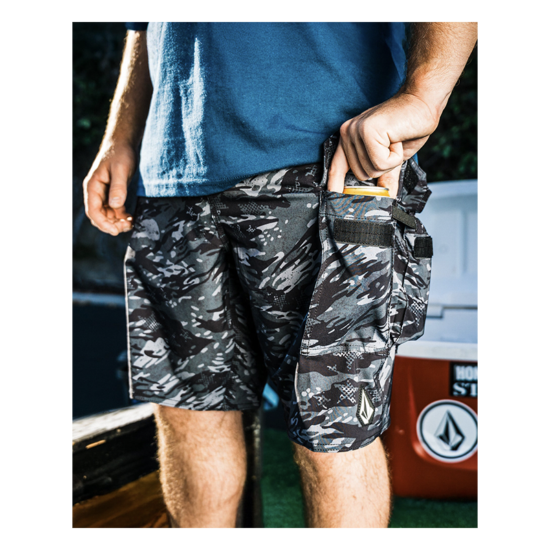 Person wearing camouflage shorts with a blue shirt, standing in front of a blurred background.