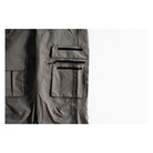 Close-up of dark gray cargo pants showing a zippered pocket with black elastic bands on a white background.