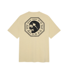 A beige short-sleeve t-shirt shown from the back, featuring a large black graphic of a skull inside an octagonal frame.