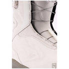 Close-up of a snowboard boot in off-white leather and gray mesh, showing the lace-up closure and textured paneling.