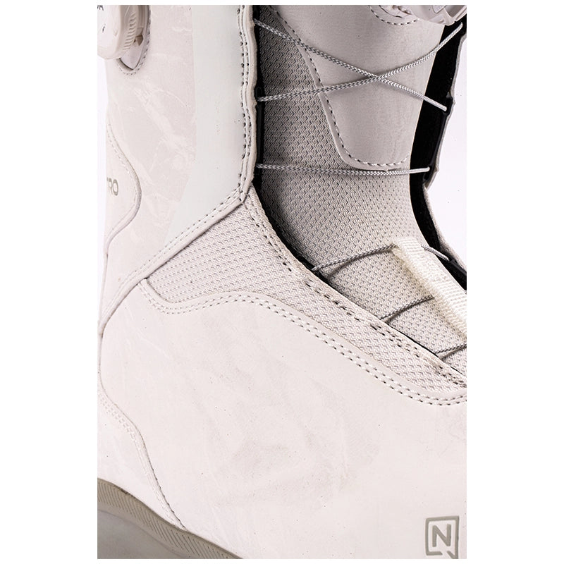Close-up of a snowboard boot in off-white leather and gray mesh, showing the lace-up closure and textured paneling.