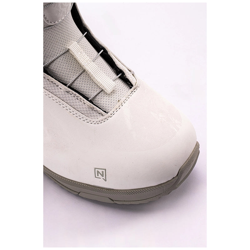 A close-up shot of a snowboard boot showing the toe area, featuring a glossy white upper, a textured gray sole, and a small stylized 'N' logo on the side.