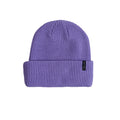 A purple ribbed knit beanie hat with a folded cuff, featuring a small black brand tag on the side, set against a plain white background.